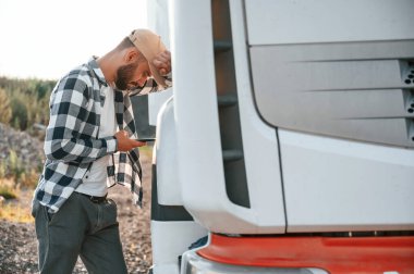 Yorgun hissediyorum. Akıllı telefon kullanıyor. Genç kamyon şoförü gündüz vakti aracıyla geliyor..