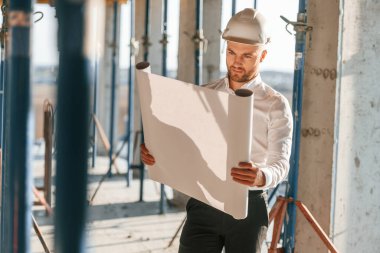 Yönetici resmi giysiler içinde. Planı kontrol altında tutuyoruz. Gündüz vakti inşaatta çalışan bir adam var..