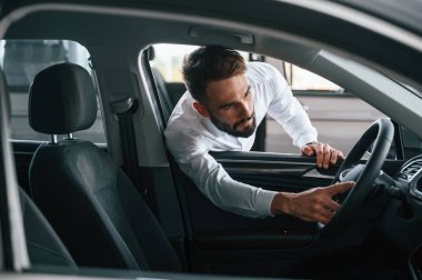 Otomobilin içine bakıyorum. Beyaz elbiseli genç adam araba galerisinde..