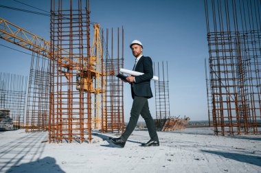 Kağıdı plan ve tabletle tutarak. Resmi kıyafetli bir işadamı gün içinde şantiyede olacak..