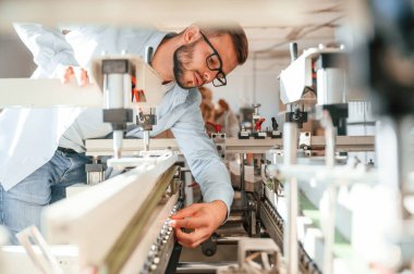 Kesme makinesini kullanma süreci. Beyaz elbiseli matbaacı içeride..