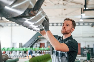 Dilimleme parçaları kontrol ediliyor. Üniformalı adam iş yerinde tarım tekniğinin detaylarını geliştiriyor..