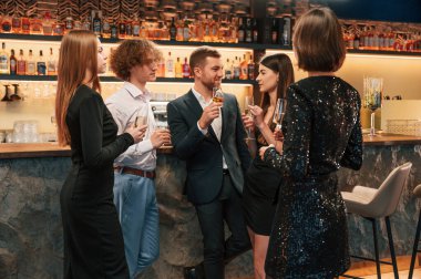 Konuşmak, gülümsemek, eğlenmek. Güzel giyinmiş bir grup insan içeride yeni yılı kutluyorlar..