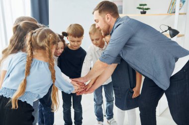 Gelecekteki başarı için el hareketi yapmak. Okulda öğretmenle birlikte bir grup çocuk öğrenci..