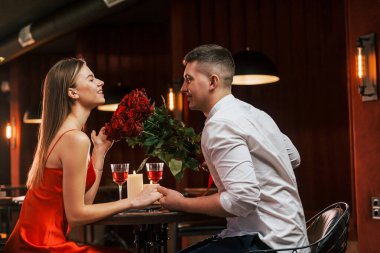 Kırmızı elbiseli ve beyaz gömlekli. Romantik çift restoranda yemek yiyor..