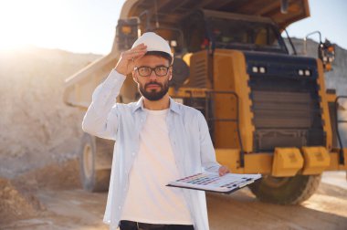 Arkasında büyük yük treni var. Üniformalı adam gündüz taş ocağında çalışıyor..