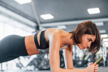 Tahta egzersizi yapıyorum. İnce vücutlu spor elbiseli kadın spor salonunda..