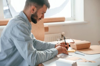 Yeni bir tasarım çizmek için kalem kullanıyorum. Beyaz elbiseli matbaacı içeride..