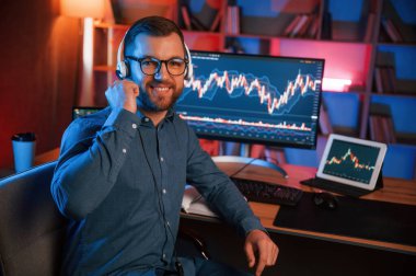 Hisse senedi tüccarı kapalı alanda bilgisayar başında çalışıyor. Değişim ve para kavramı.