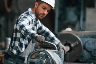 İşletim makinesiyle çalışıyor. Üniformalı fabrika işçisi içeride..