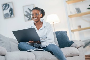 Çevrimiçi bağlantı. Beyaz gömlekli Afro-Amerikan kadın evde..