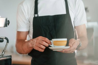 Manzarayı kapat. Bir fincan kahve tutuyorum. Beyaz gömlekli ve siyah önlüklü kafe çalışanı içeride..