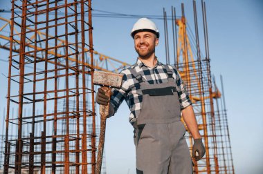 Elinde büyük bir çekiçle. Gündüz vakti inşaatta çalışan bir adam var..