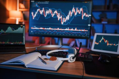 Ekranda borsa grafiği olan bilgisayar neon ışıklı karanlık odada..