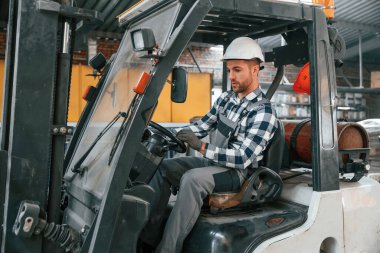 Forklift sürücüsü. Üniformalı fabrika çalışanı içeride..