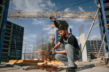 Paslı metal parçalarıyla çalışıyorum. Üniformalı adam şantiyede..