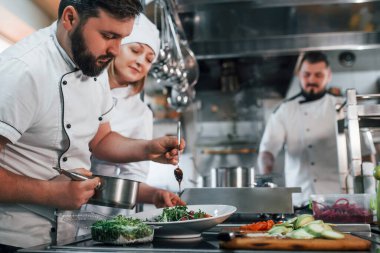 Üç kişi. Vejetaryen salatası. Profesyonel aşçı mutfakta yemek hazırlıyor..