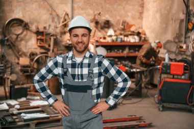 Ayakta, eller belde. Üniformalı fabrika çalışanı içeride..
