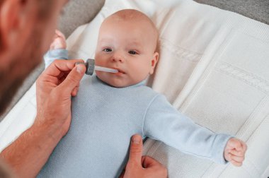 Pipetle ilaç veriyor. Yeni doğmuş bebeğiyle baba içeride. Bekar baba kavramı.