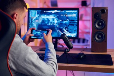 Akıllı telefonu kullanıyordu. Evde FPS nişancı oyunu oynayan çevrimiçi flamalar.