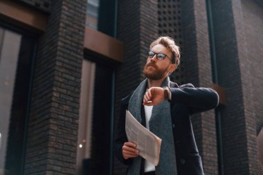 Kontrol zamanı. Sakallı ve gözlüklü şık adam binanın yanında..