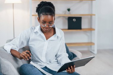 Kanepede oturuyordum. Beyaz gömlekli Afro-Amerikan kadın evde..