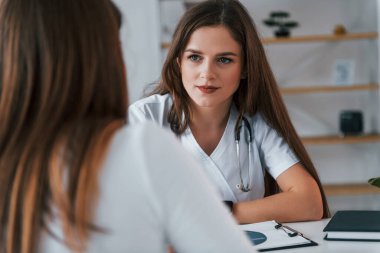 Kadına danışmak için. Ofiste beyaz önlüklü profesyonel bir sağlık görevlisi var..