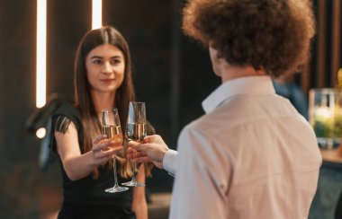 Genç kadın ve erkek kadeh kaldırarak kutlama yapıyorlar..