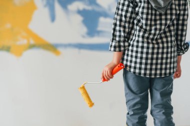 Manzarayı kapat. Küçük çocuk ev odasında duvarları boyuyor..