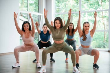 Ellerini kaldır. Spor salonunda spor yapan bir grup kadın..