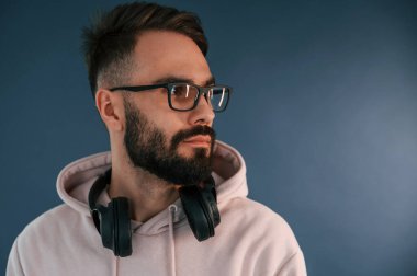 Adam gözlüklü ve kulaklıklı. Yakışıklı adam stüdyoda mavi arka planda..