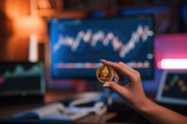 Bitcoin 'i bilgisayar ekranına ve tablete karşı grafiklerle tutan kadının elini kapat.