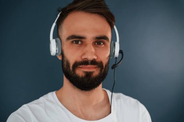 Kulaklıkla. Yakışıklı adam stüdyoda mavi arka planda..