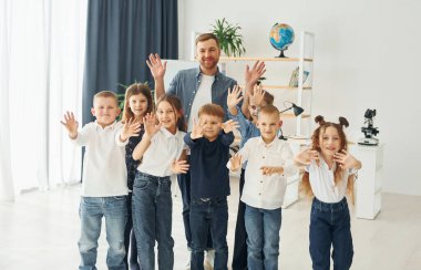 Merhaba jestleri gösteriyorum. Okulda öğretmenle birlikte bir grup çocuk öğrenci..