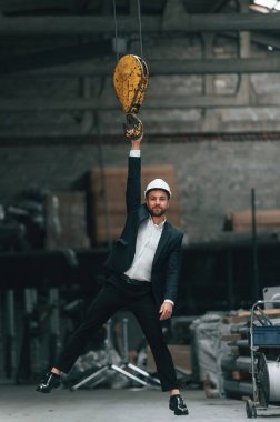 Vinç kancasına asılıydı. Fabrikada resmi siyah giyim müdürü..