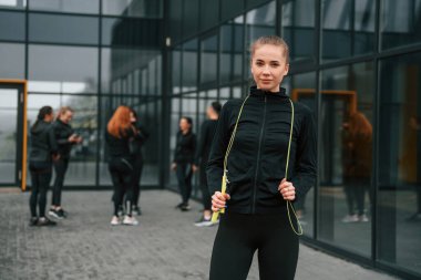 Bir grup sportif kadın dışarıda, siyah binanın yakınında..