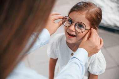 Yeni gözlük takıyor. Kadın ve kız gözlük dükkanında..