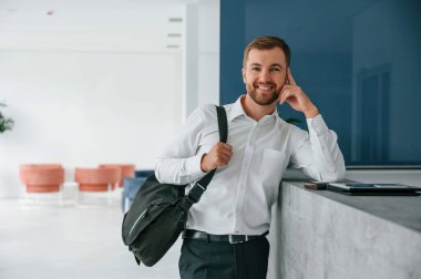 Resepsiyonda bekliyor. Resmi kıyafetli şık adam içeride..