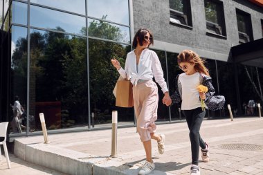 Genç anne kızıyla birlikte dışarıda alışveriş yapıyorlar..