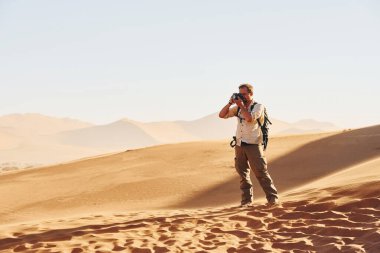 Fotografik ekipmanlarla. Günlük giysiler içindeki erkek turist Afrika çöllerinde, Namibya 'da..
