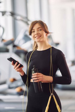 Akıllı telefon sizin ellerinizde. Spor elbiseli genç bir kadın spor salonunda spor yapıyor..