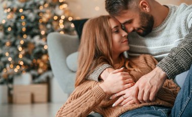 Kanepeye uzanıp kucaklaşmak. Güzel genç çift yeni yılı evde kutluyor..