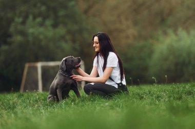 Genç esmer kız köpeğiyle dışarıda yürüyüş yapıyor..