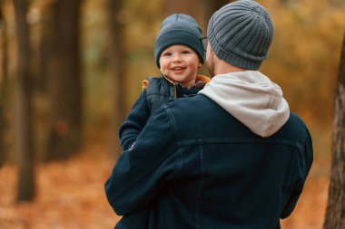 Kalın giysiler içinde. Baba ve küçük oğlu gündüz vakti dışarıda beraberler..
