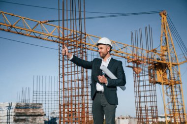Başparmağımı gösteriyorum. Resmi kıyafetli bir işadamı gün içinde şantiyede olacak..