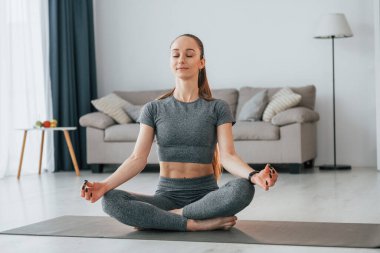 Ev içi oda. İnce vücutlu ve yoga elbiseli genç bir kadın evde..