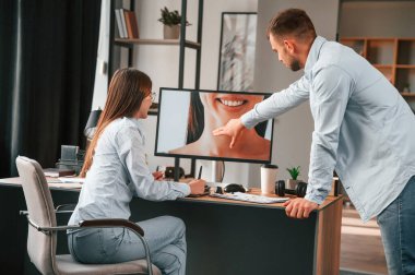 Kadının portresini yeniliyorum. İki genç tasarımcı ofiste birlikte çalışıyor..