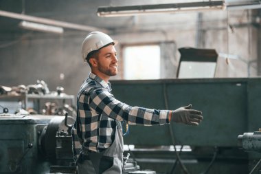 Üniformalı, dost canlısı fabrika çalışanı içeride el ele veriyor..