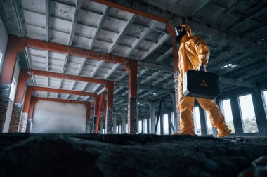 Aşağıdan bak. Kıyamet sonrası binanın harabelerinde kimyasal koruma kıyafeti giymiş bir adam..