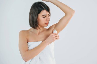 Top deodorantı kullanıyor. Genç esmer, beyaz arka planda..